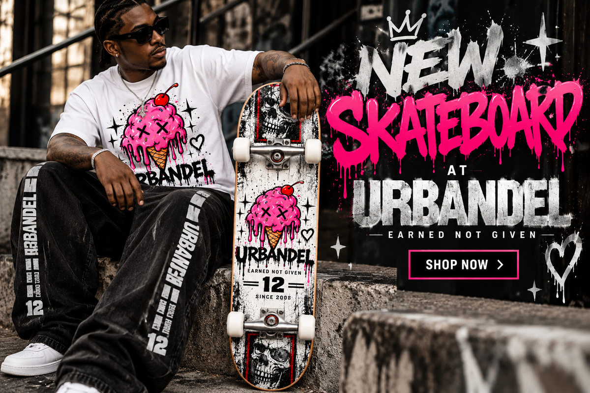 A man wearing a white URBANDEL graphic t-shirt and black pants sits on concrete steps holding a skateboard with a matching pink and white graphic design. The background features a dark wall with graffiti-style text reading 'NEW SKATEBOARD AT URBANDEL' and a 'SHOP NOW' button.