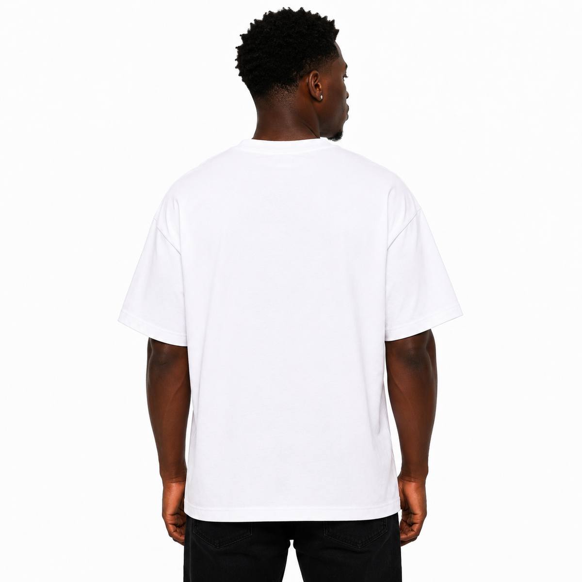 A man viewed from behind wearing a plain white short-sleeve t-shirt and black pants, standing against a solid white studio background.